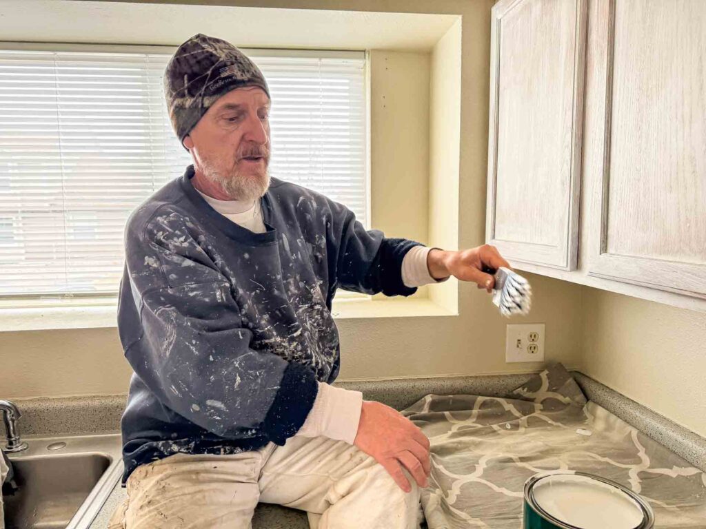 a man sitting on a counter with a paint brush