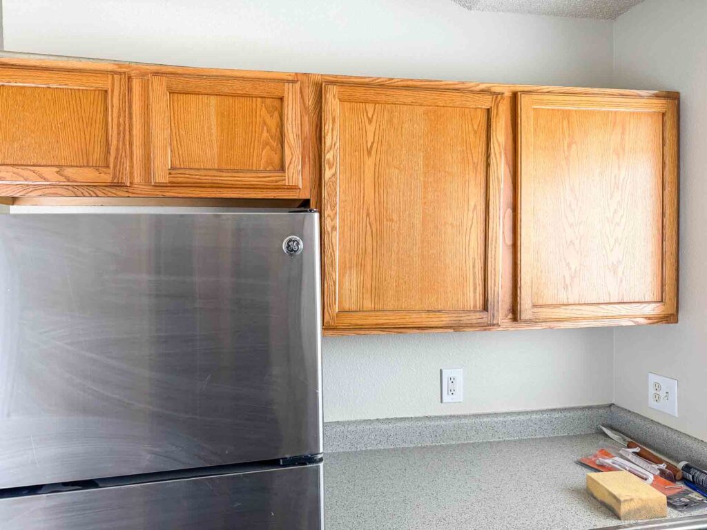 a kitchen with a refrigerator and wooden cabinets