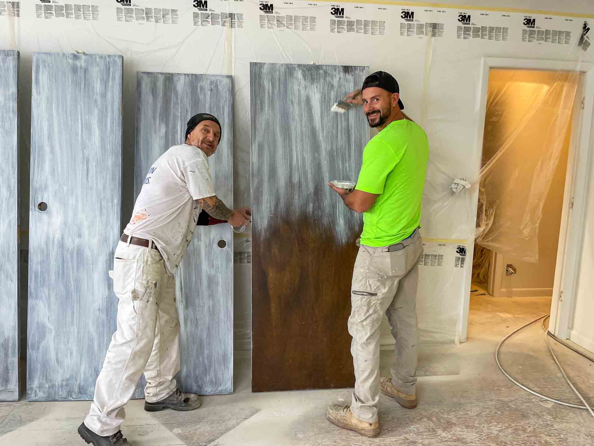 Two men are painting doors